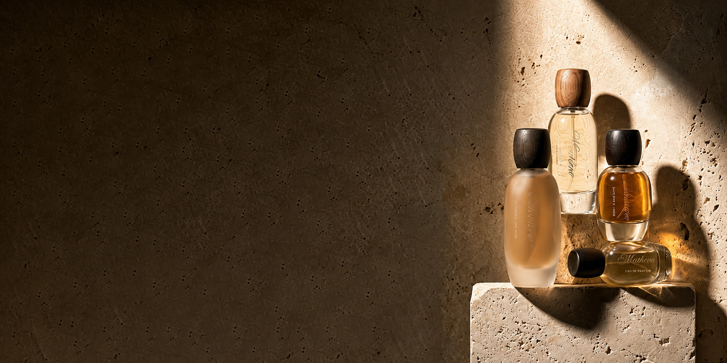 Perfume bottles on travertine in a shaft of light